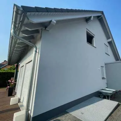 Weißgraue Putzfassade eines Einfamilienhauses mit Satteldach