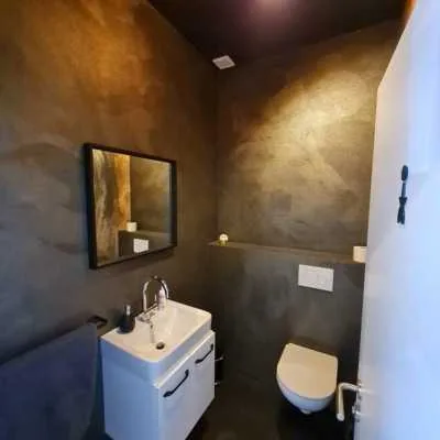Gäste-WC mit fugenloser Designspachtel in Goldbraun und Beton-Optik