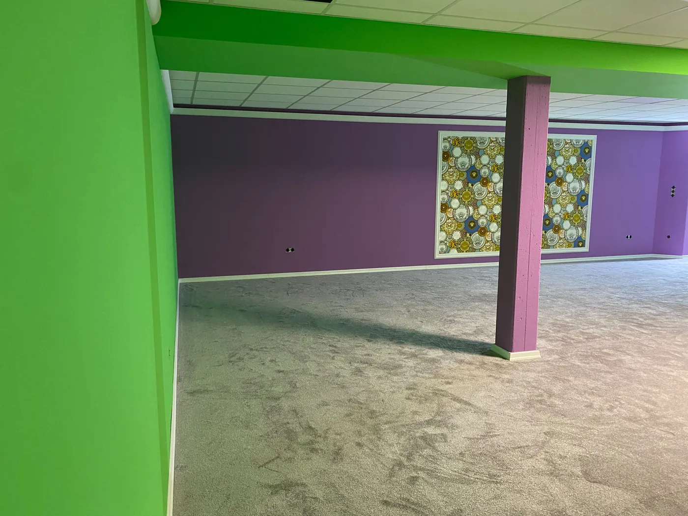 Yogaraum mit grün-lila abgesetzten Wänden, Säulen und gerahmten Designertapeten-Flächen